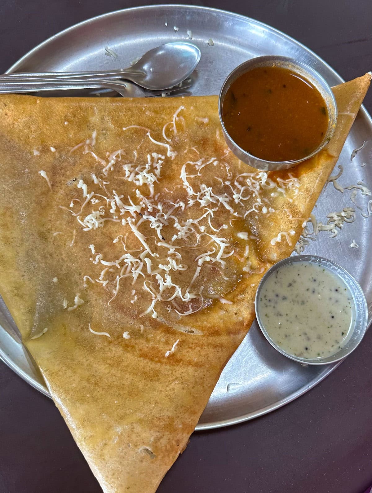 Masala dosa served with sambar and chutney in a steel plate.