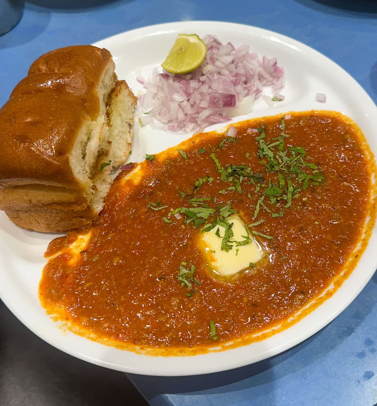 Pav bhaji served with a side of onions and lime.