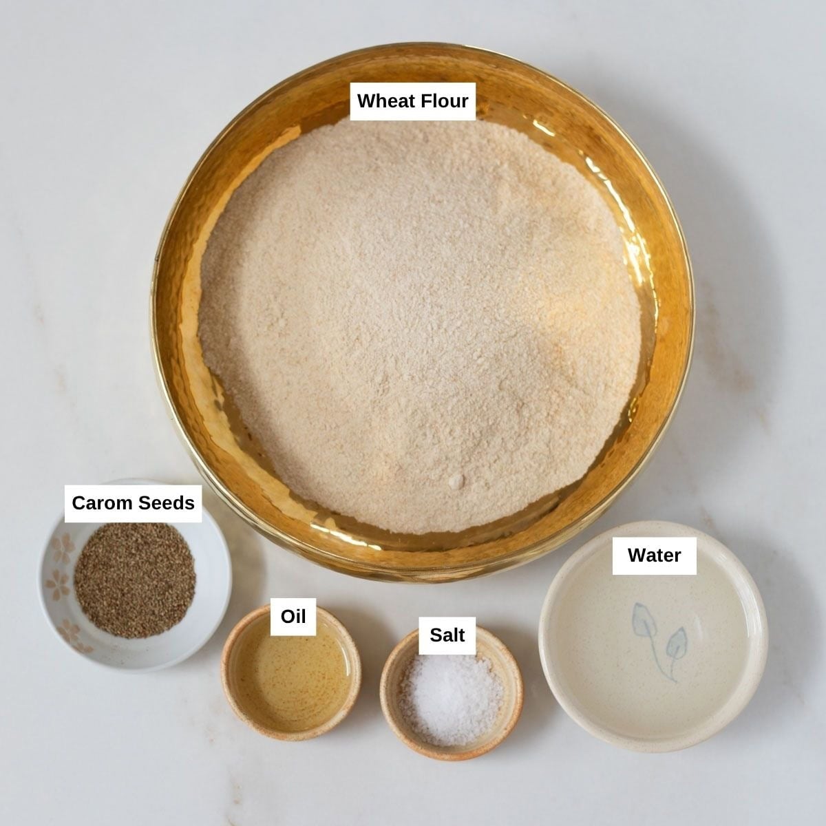 Ingredients to make fluffy puri such as whole wheatb flour, salt, ajwain, oil, and water.