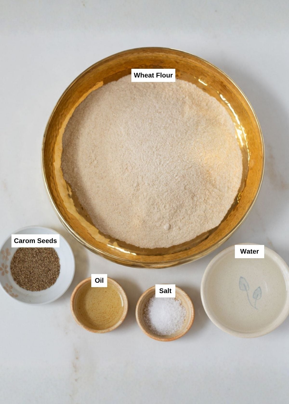 Ingredients to make fluffy puri such as whole wheatb flour, salt, ajwain, oil, and water.