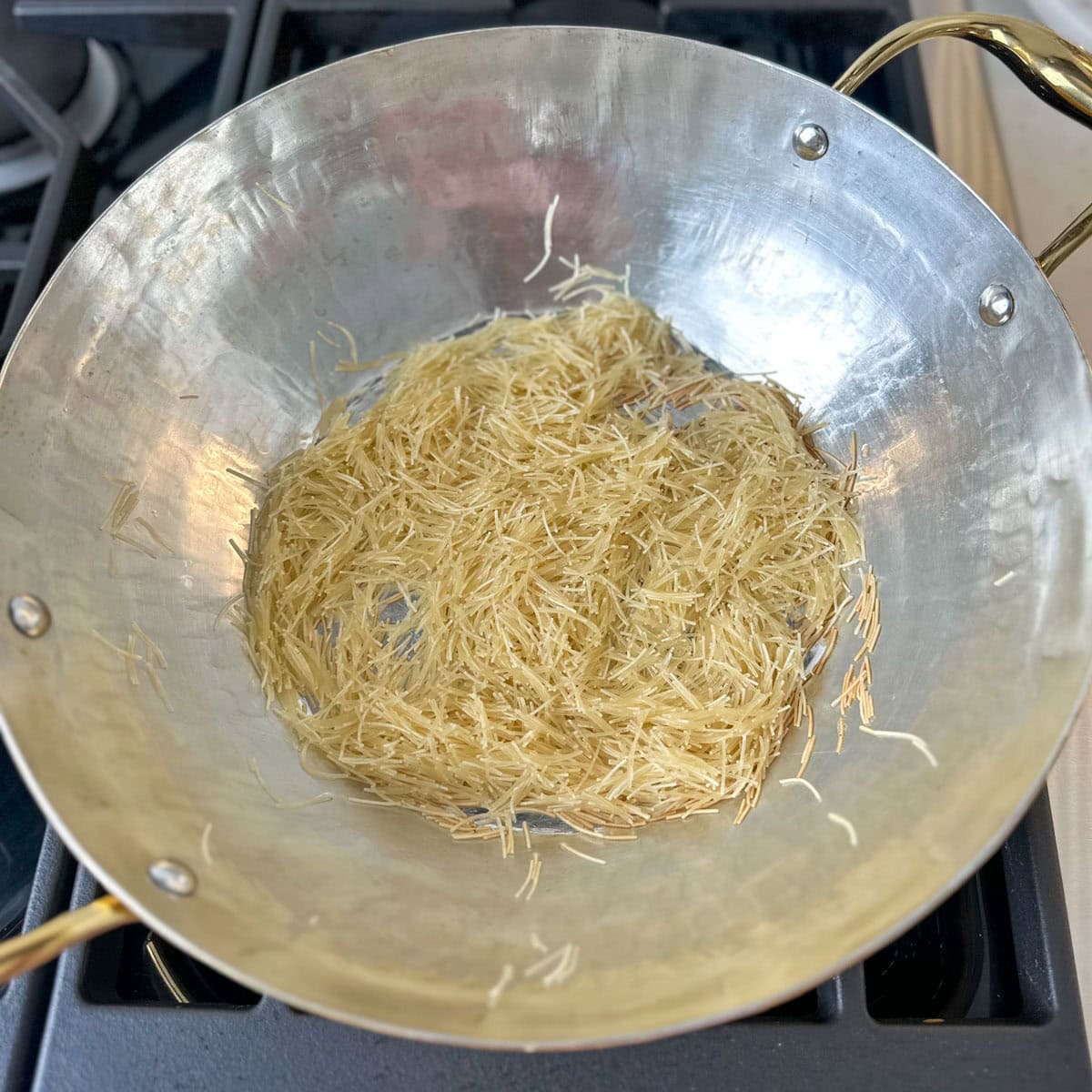 Vermicelli being roasted in a brass pan to make kheer.