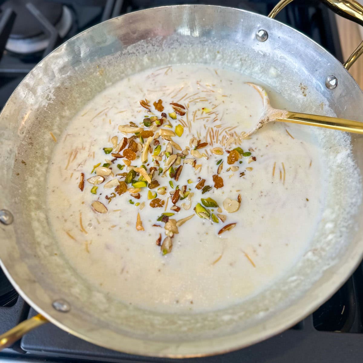 Toasted nuts added to Seviyan Kheer made in a brass pan.