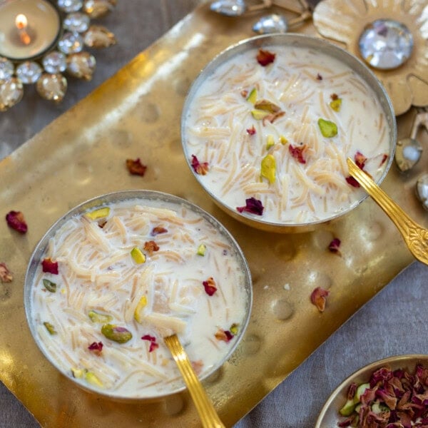 Instant pot vermicelli kheer served in 2 brass bowls garnished with nuts and rose petals.