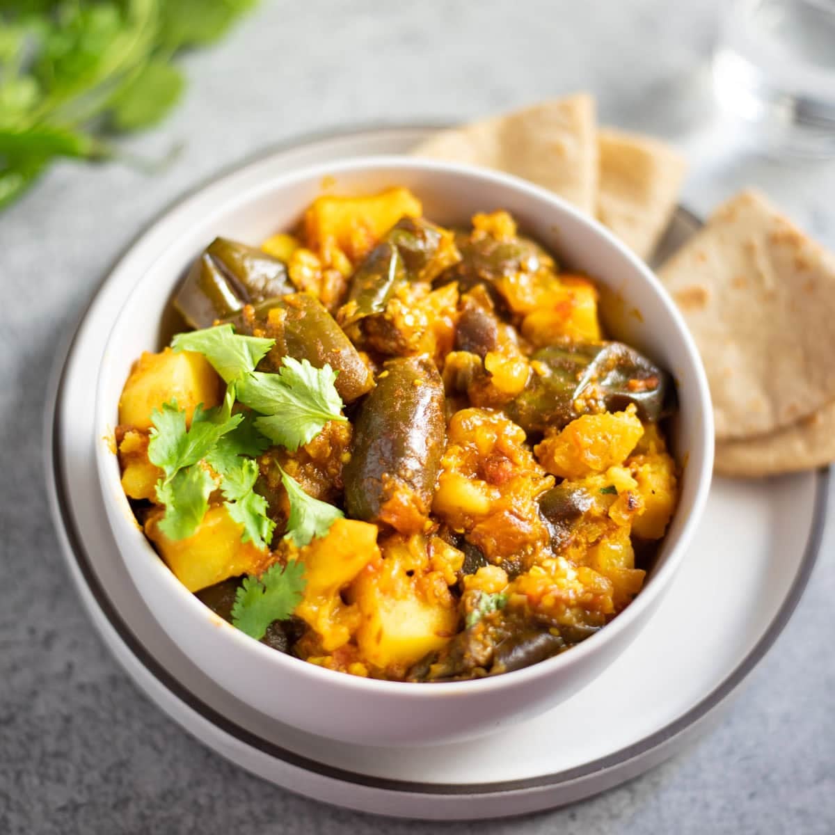 Aloo Baingan in a bowl garnished with cilantro leaves.