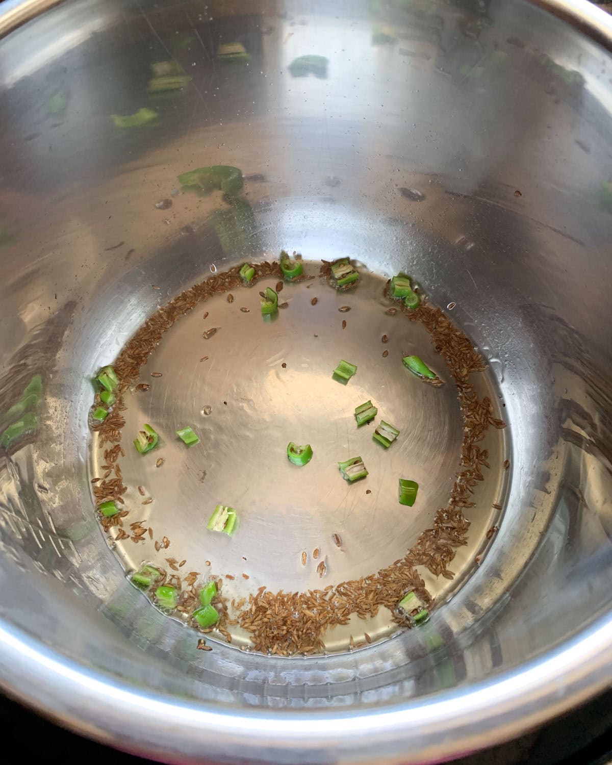 Saute cumin and green chili in oil for aloo baingan.