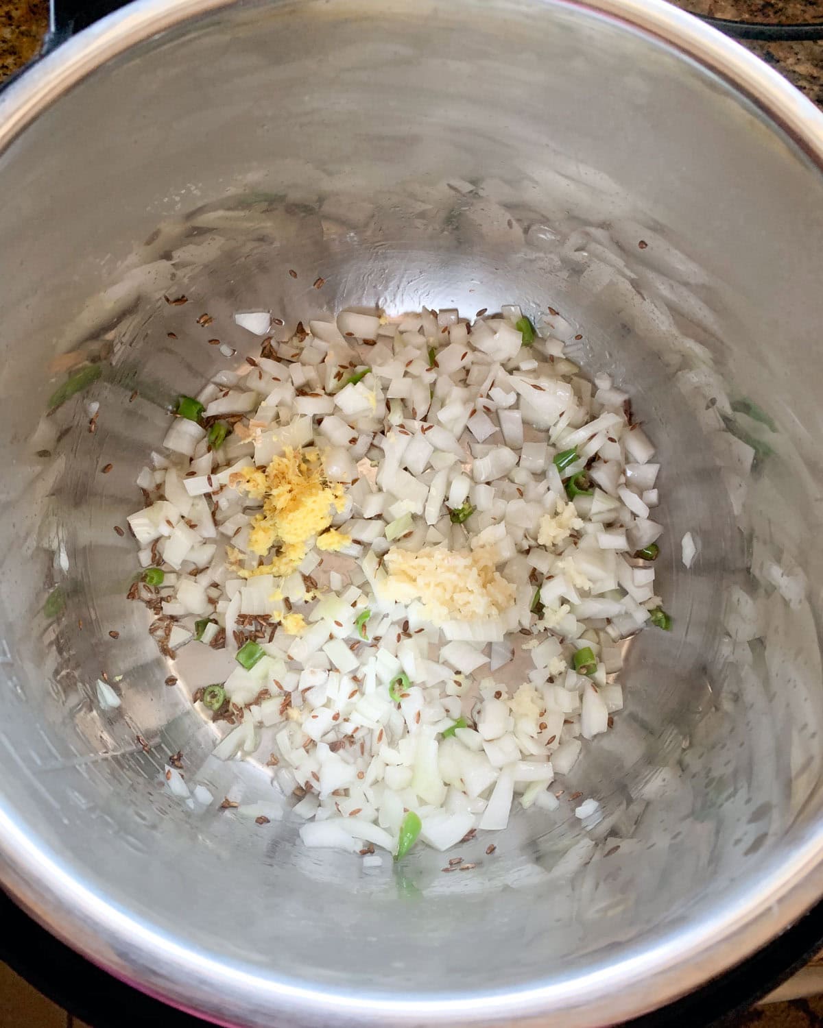 Saute onions and aromatics for aloo baingan in the pressure cooker.