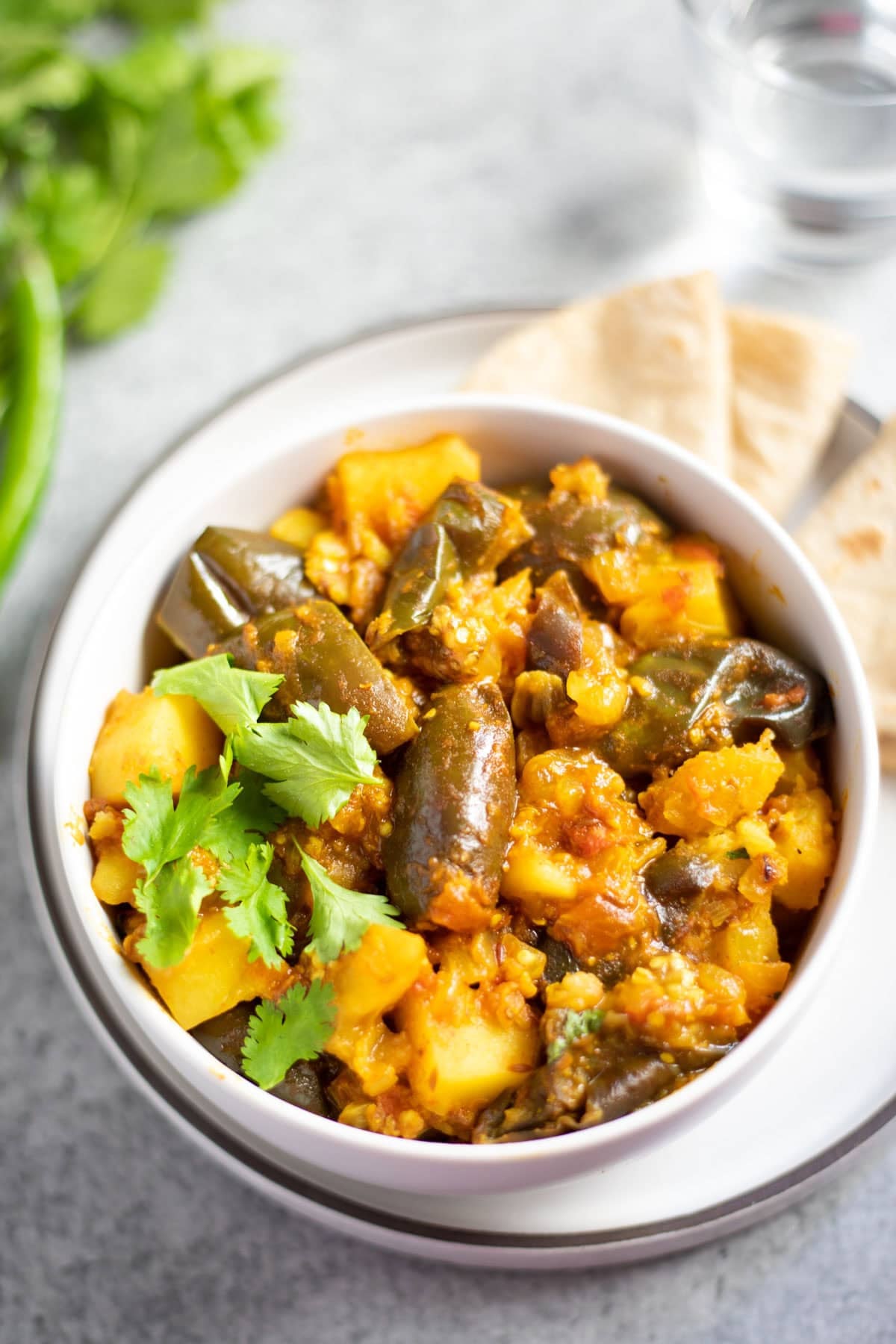 Eggplant potato curry served in a white bowl garnished with cilantro.