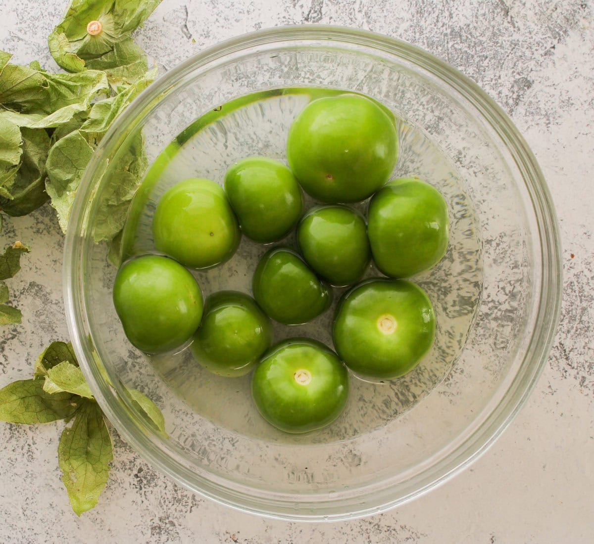 Washed tomatillo in a glass bowl.