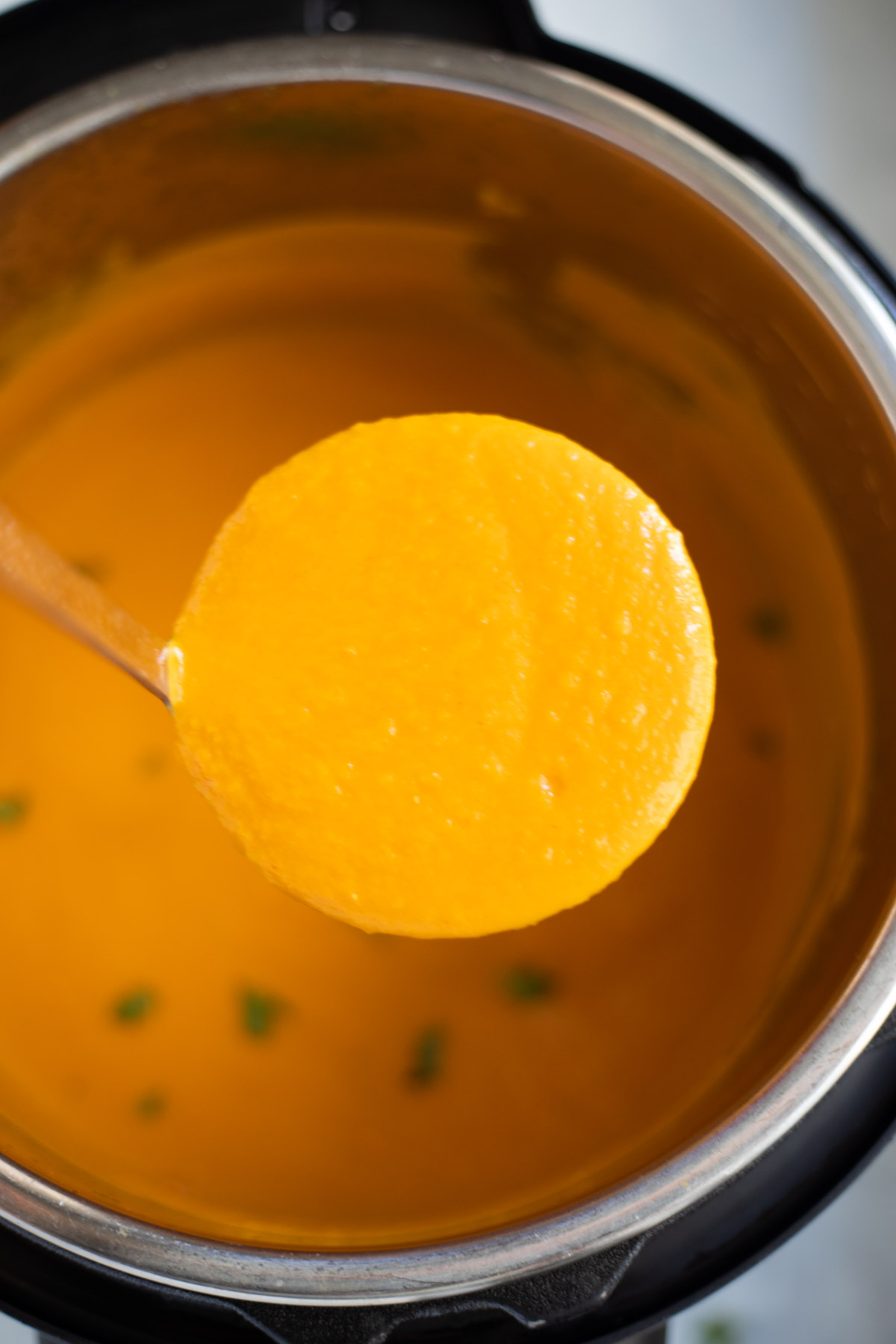 Carrot soup in a ladle above the Instant-Pot